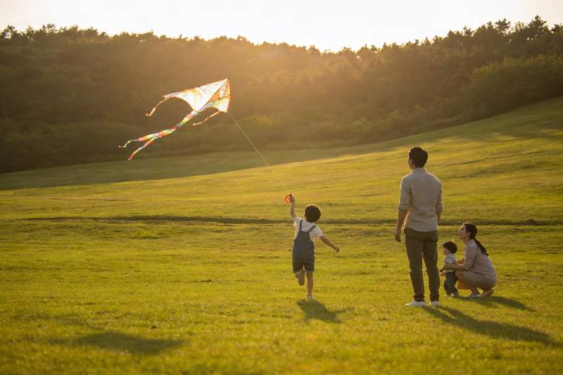夕阳下草地放风筝的温馨家庭图片