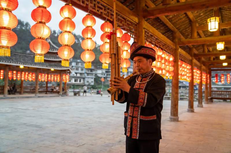 身着民族服饰男子吹奏竹笛图片