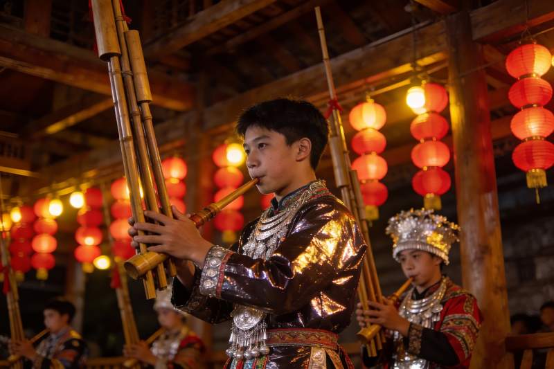 身着民族服饰的少年吹奏竹管乐器图片