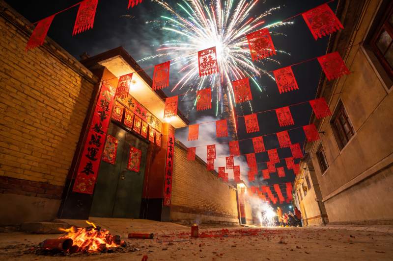 夜空烟花映照古巷喜庆场景图片