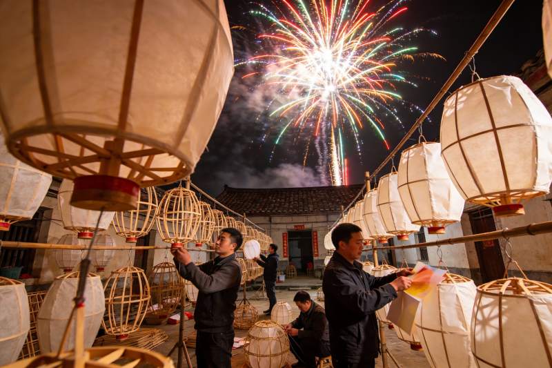 夜空烟花下制作灯笼的场景图片