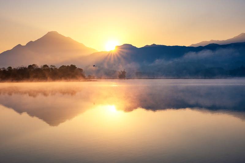 湖面日出晨雾及倒影图片