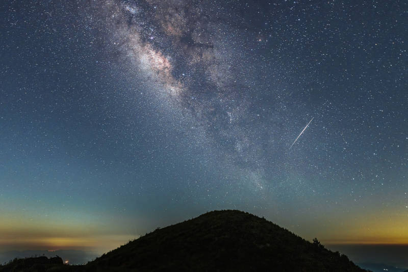山顶的银河与流星横跨夜空图片