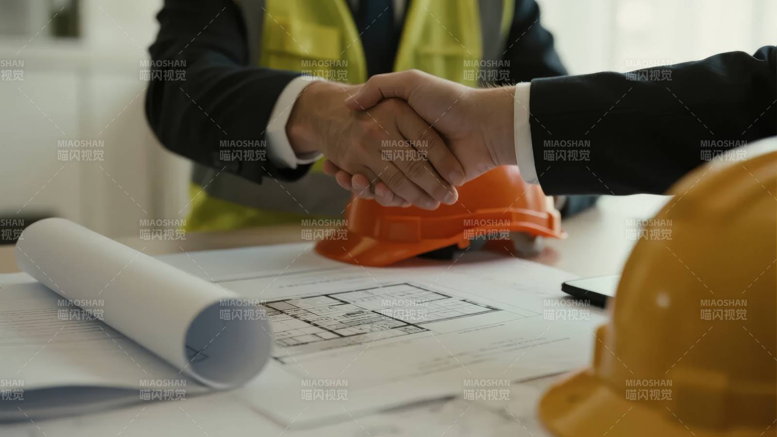 工地合作握手，蓝图与安全帽旁图片