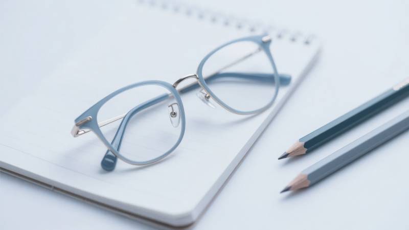 眼镜置于笔记本上，旁有铅笔图片