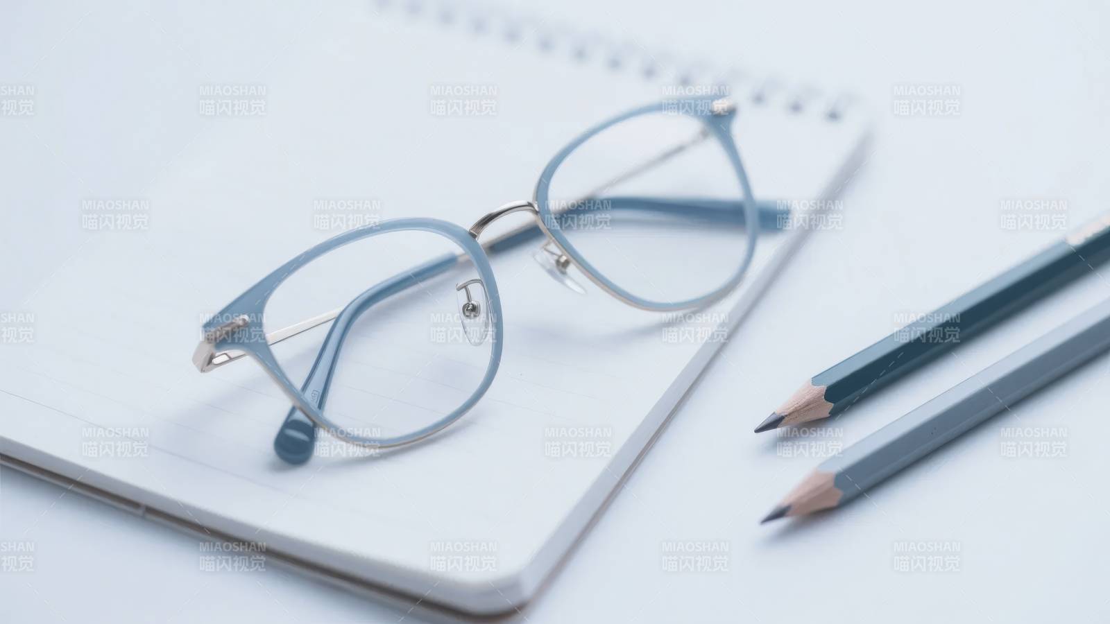 眼镜置于笔记本上，旁有铅笔图片
