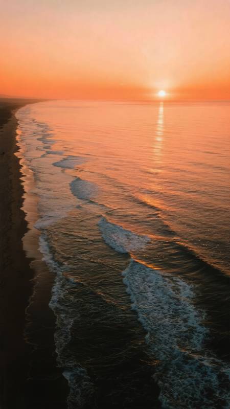 夕阳海浪映沙滩图片