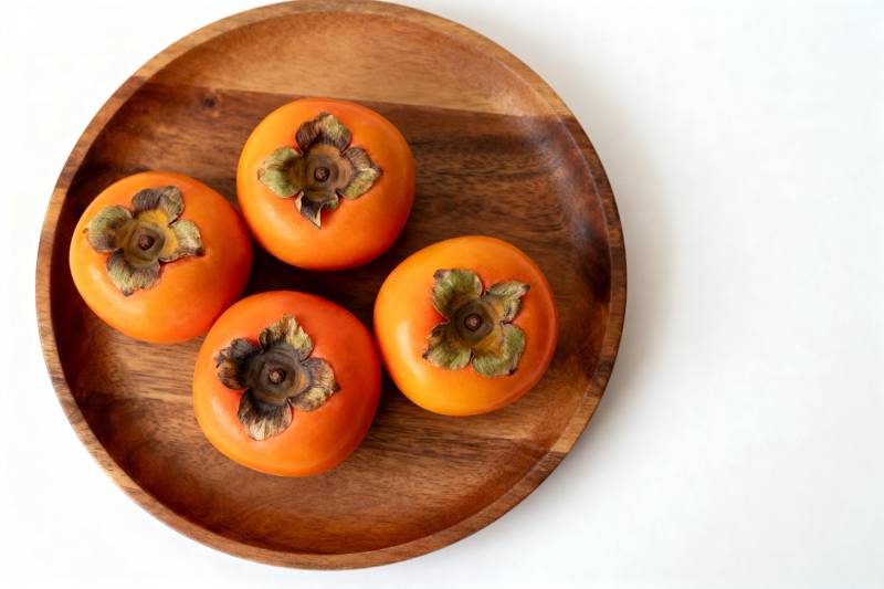 木盘上的四个柿子图片