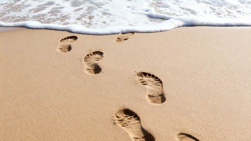 沙滩足迹迎海浪图片