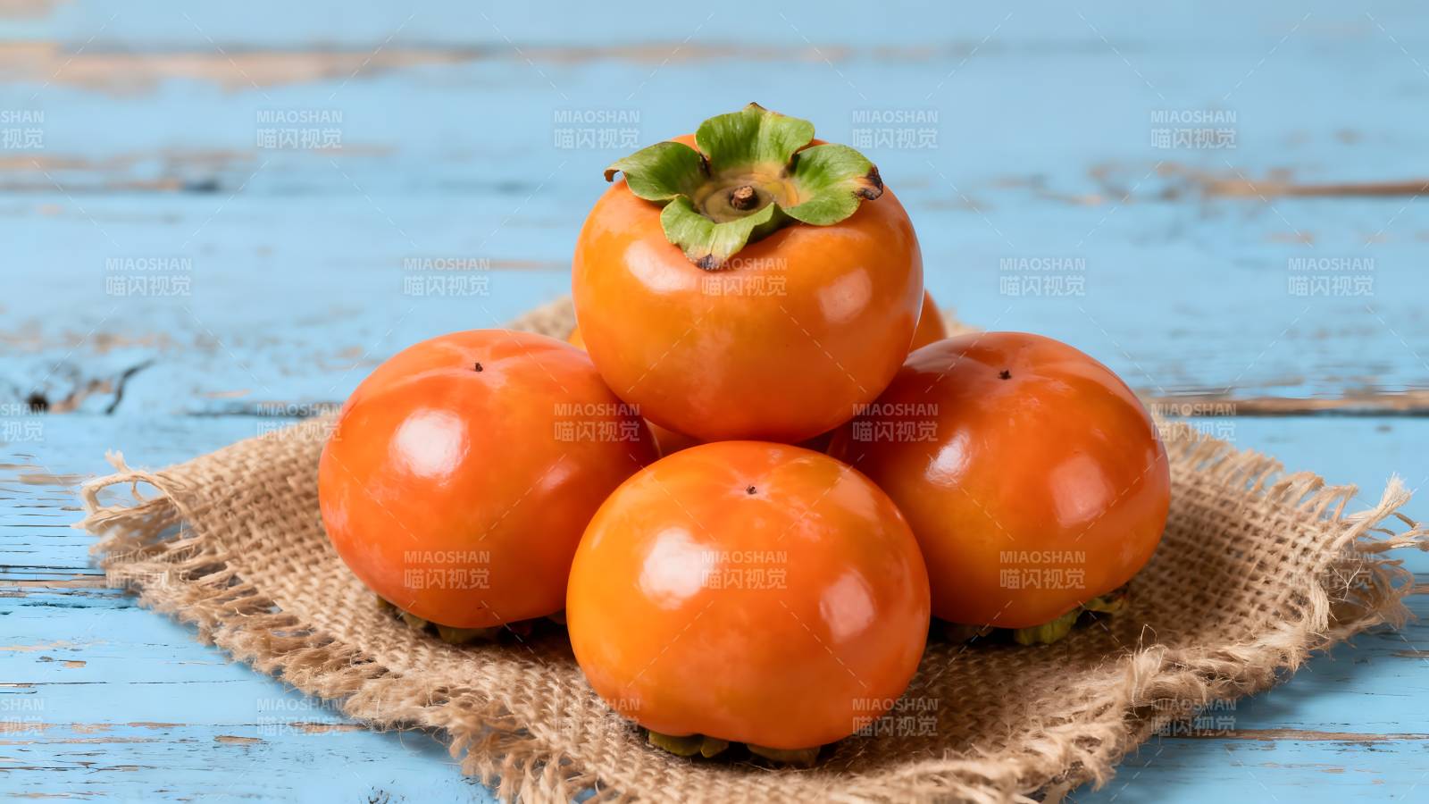 柿子堆叠在麻布上图片