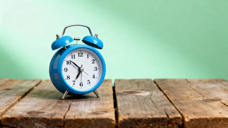 蓝色闹钟静置木桌图片