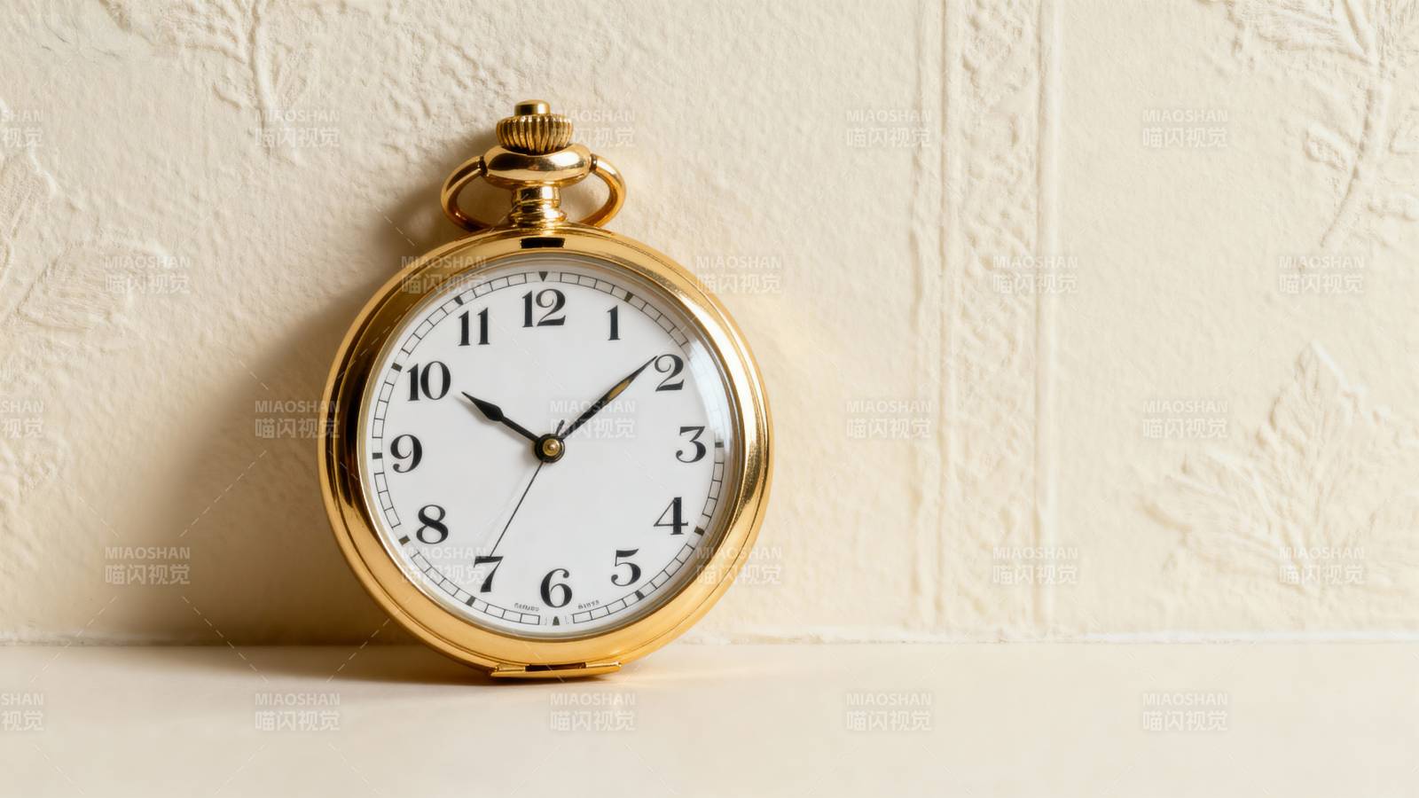 金色怀表静置墙边图片