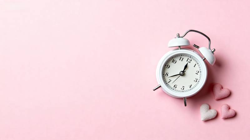 粉色背景上的闹钟与心形装饰图片