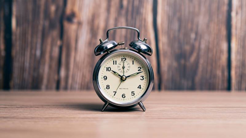 复古闹钟静置木桌图片