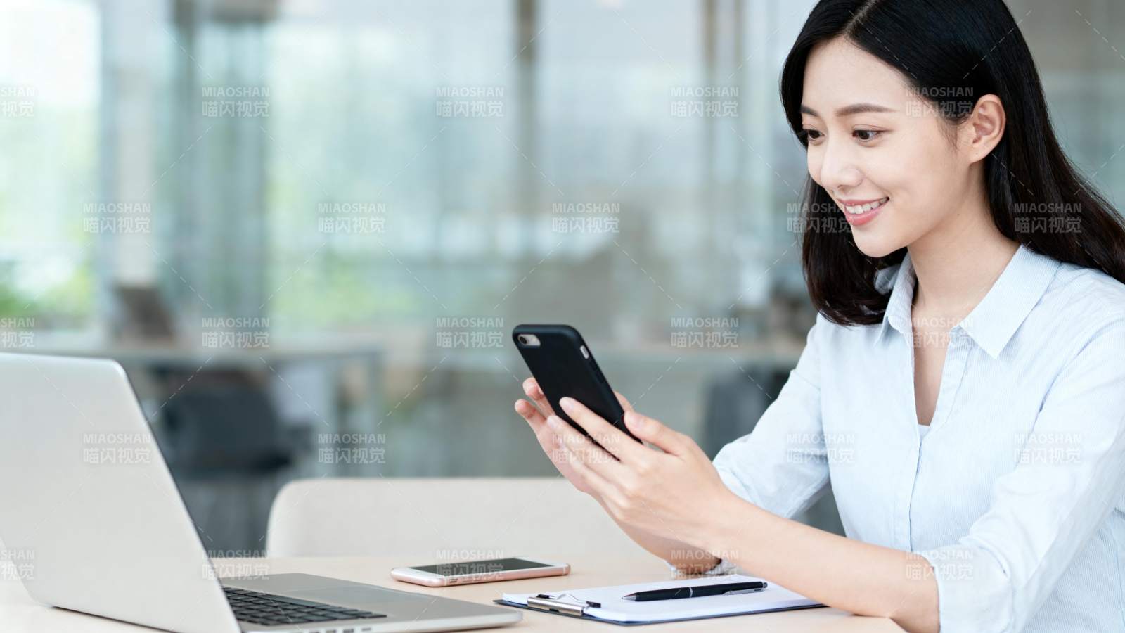 办公桌前微笑看手机图片