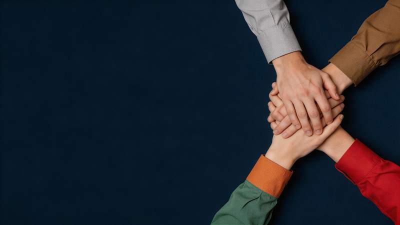 四人叠手象征团队协作与凝聚力图片