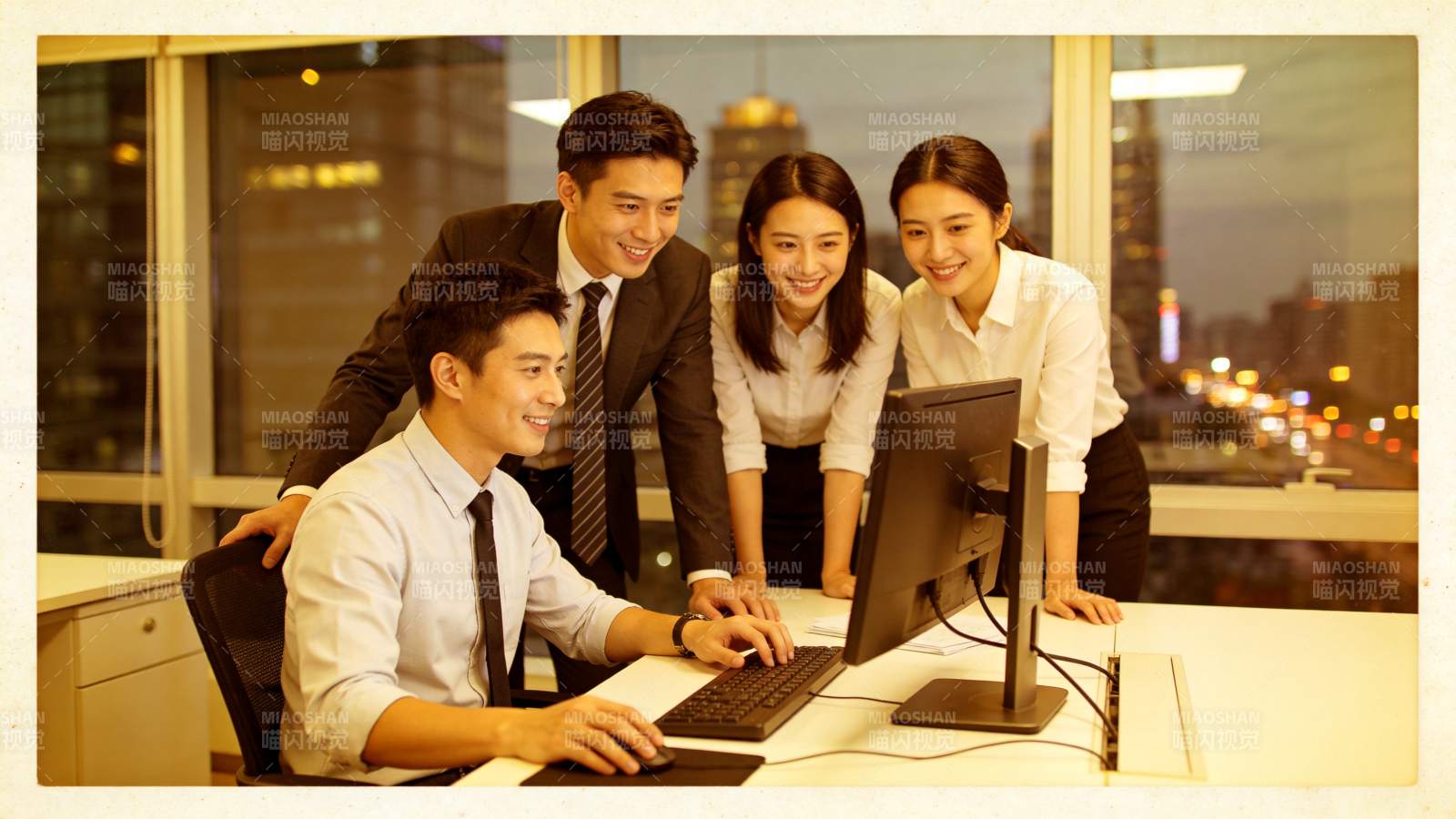 四位职场人员围看电脑屏幕协同工作图片