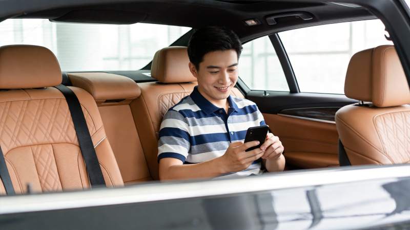 男子坐在豪华轿车后座使用智能手机图片