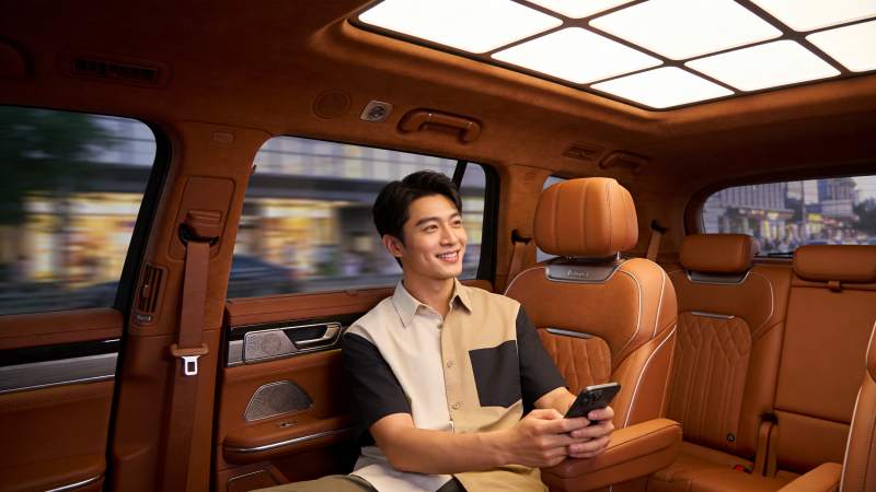 男士乘坐豪华车内手持手机微笑望向窗外图片