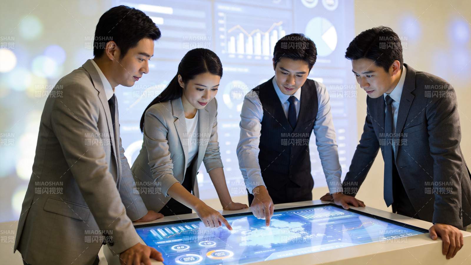 四位职场人员围绕交互式触控桌分析数据图表图片