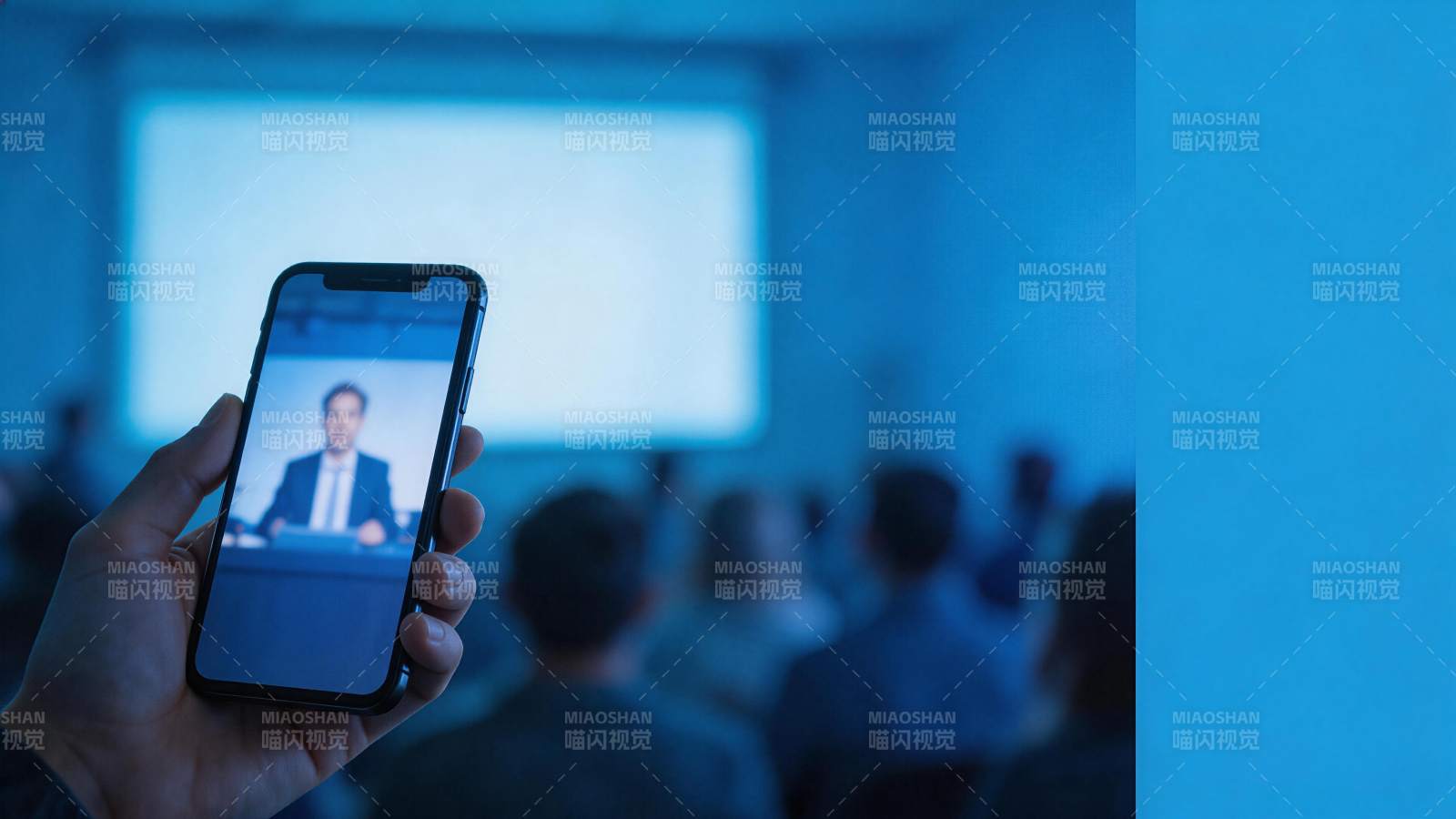 手持手机观看远程会议直播的现场场景图片