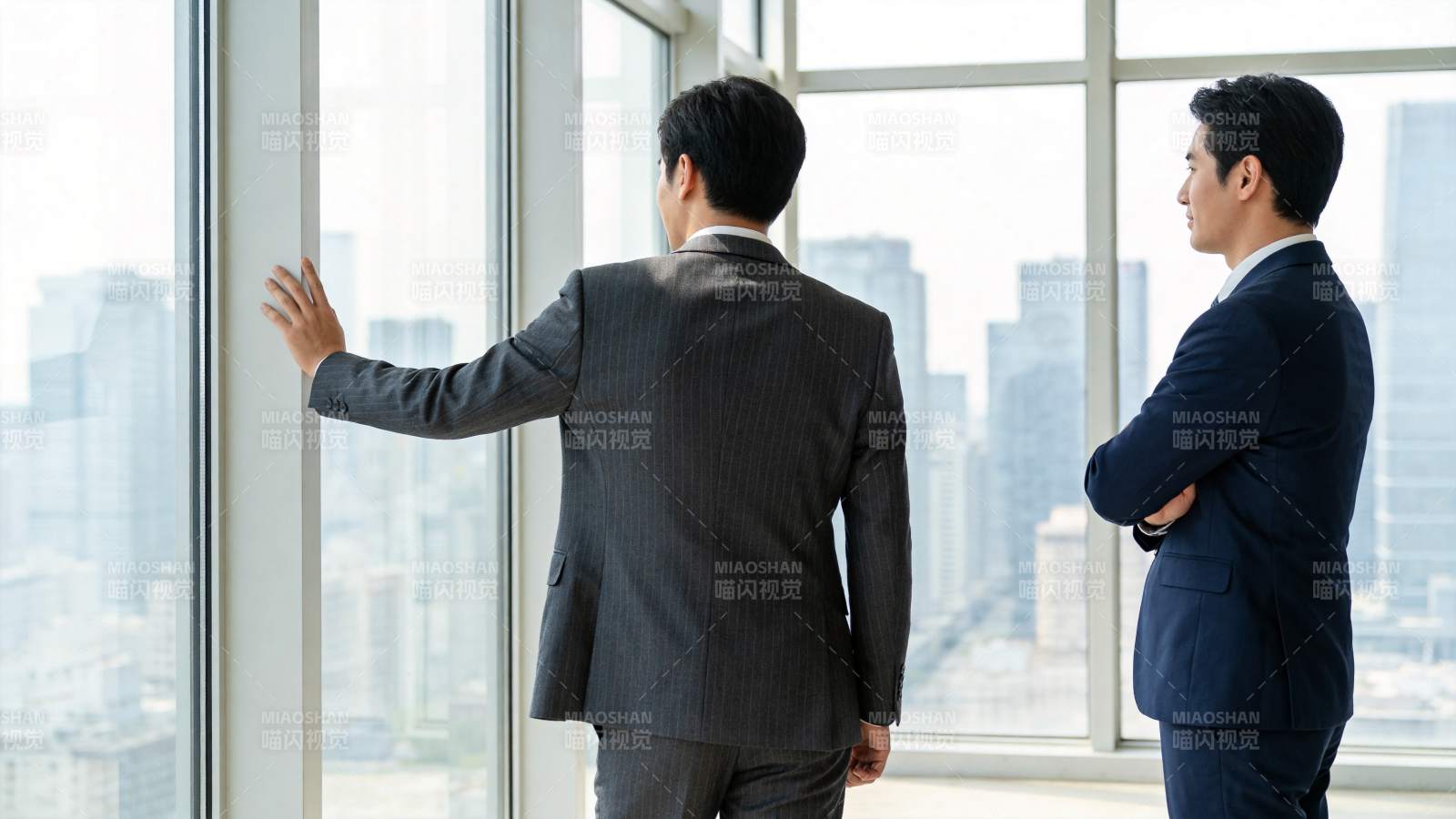 两位商务男士在高层办公室窗前眺望城市景观图片