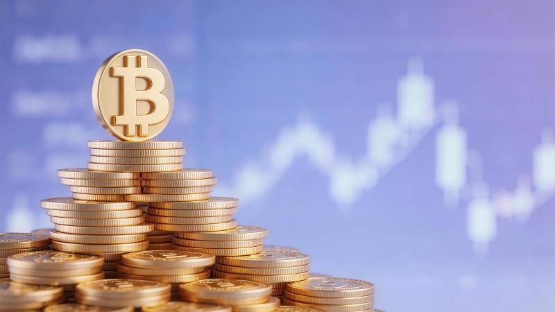 金色比特币硬币堆叠与背景金融图表图片