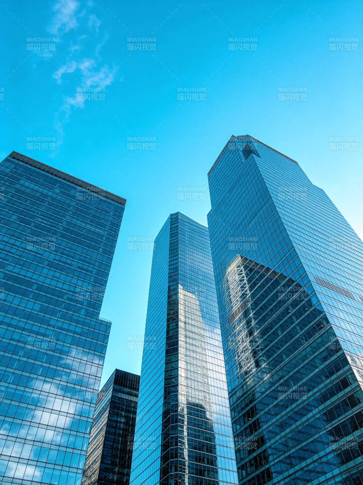 蓝天映衬下多座玻璃幕墙摩天大楼仰拍景象图片
