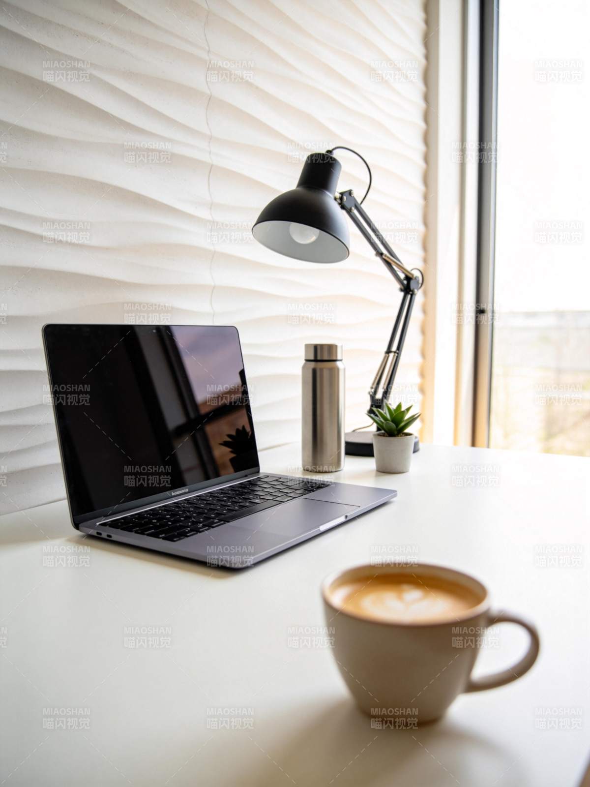 白色桌面上摆放笔记本电脑咖啡杯台灯绿植水图片