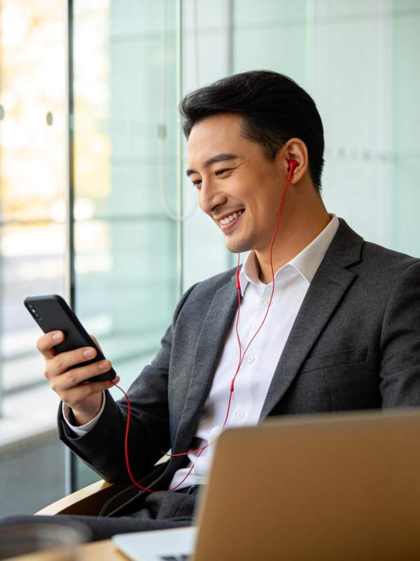 穿西装男子戴红耳机看手机微笑图片