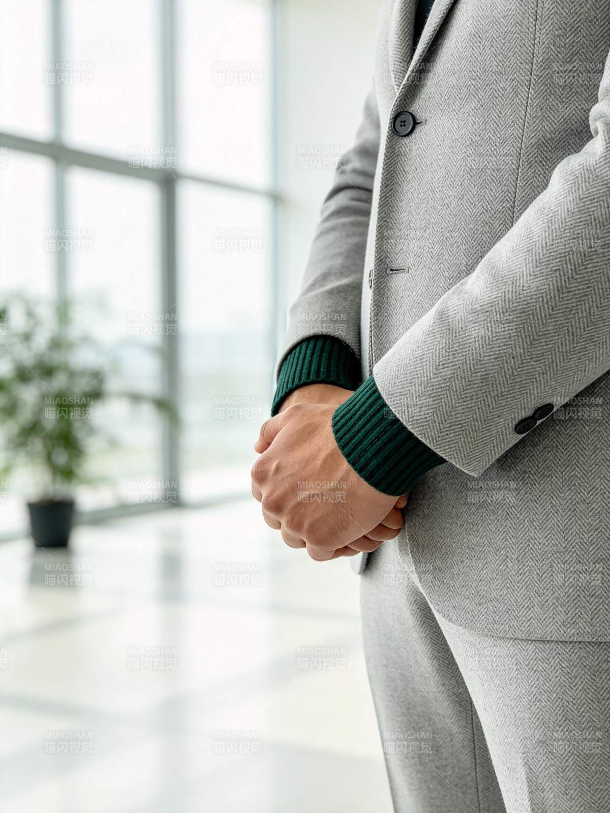 灰色西装男士双手交叠站立于明亮室内图片