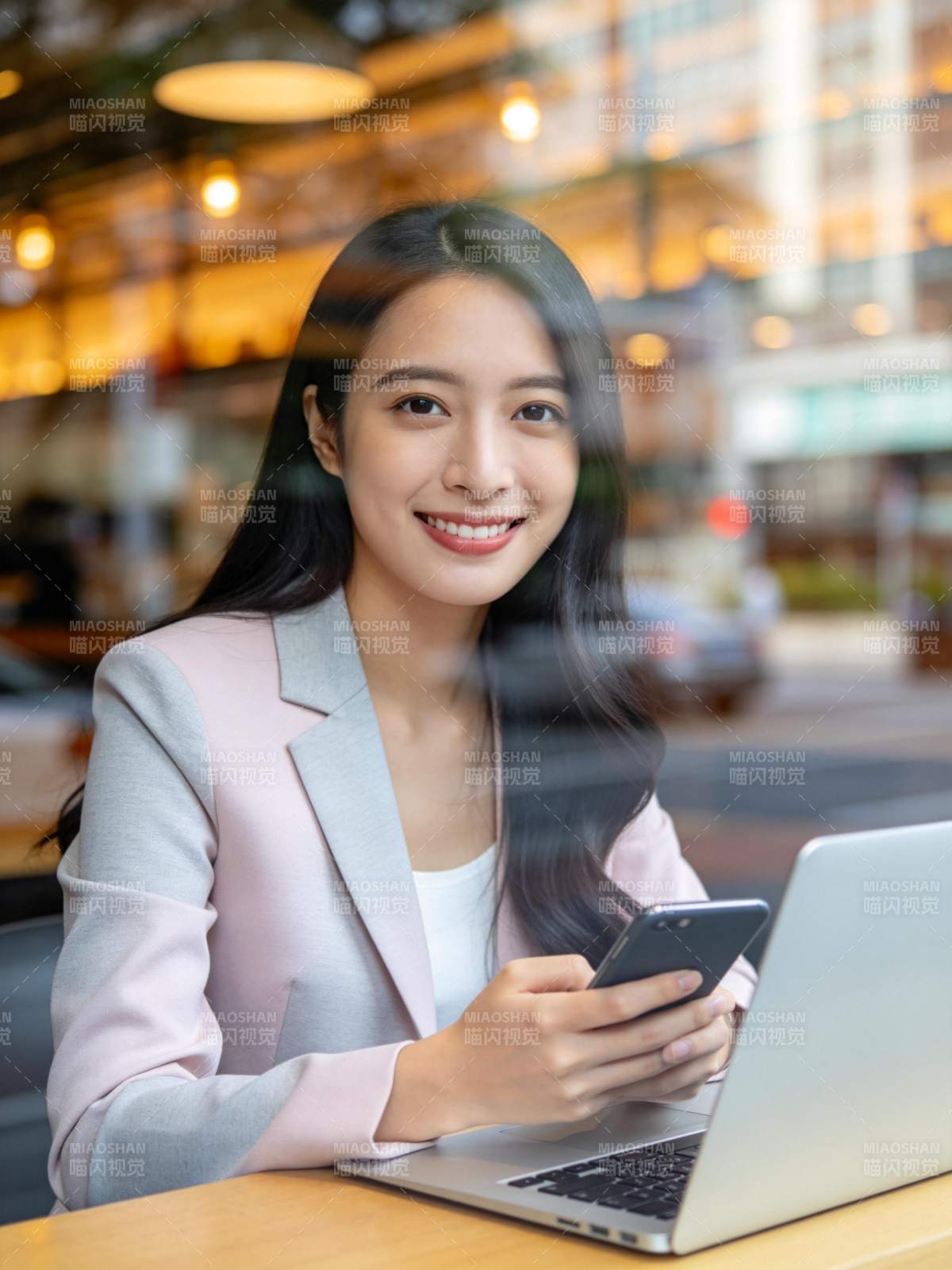 女性在咖啡馆使用手机与笔记本电脑工作图片