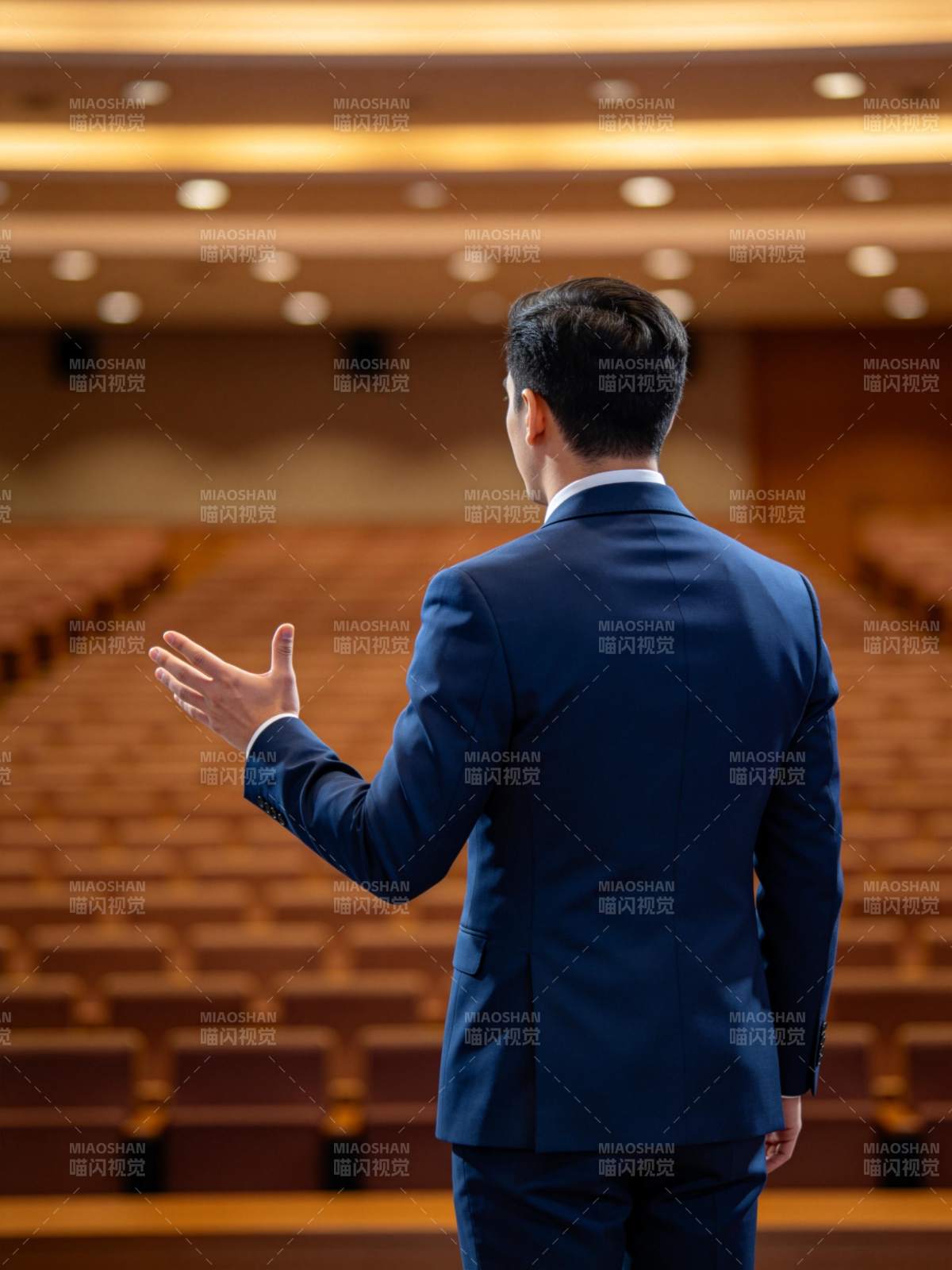 男士背对镜头在空旷礼堂中演讲手势示意图片