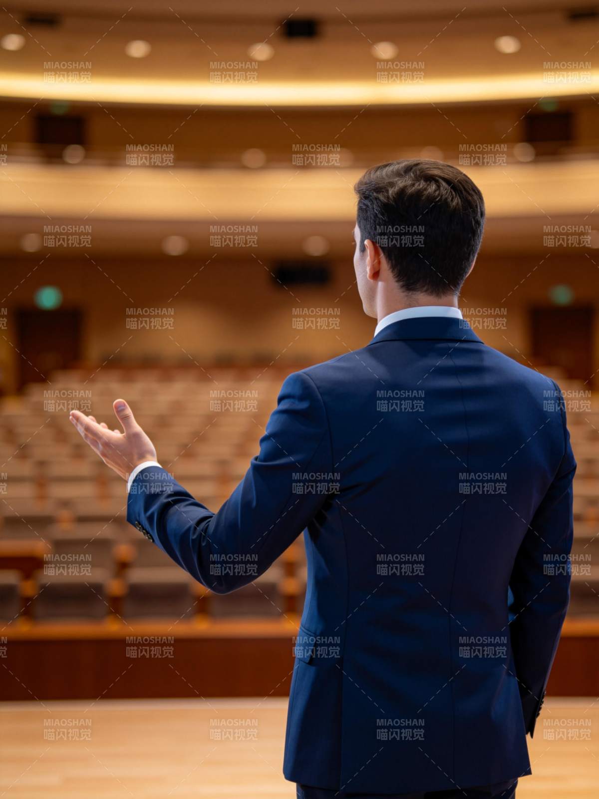 男士背对镜头在礼堂演讲手势示意图片