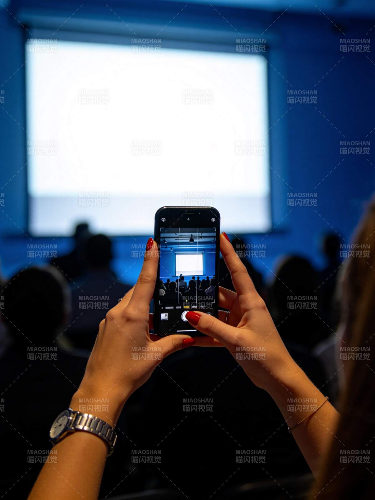 观众用手机拍摄投影屏幕上的会议画面图片