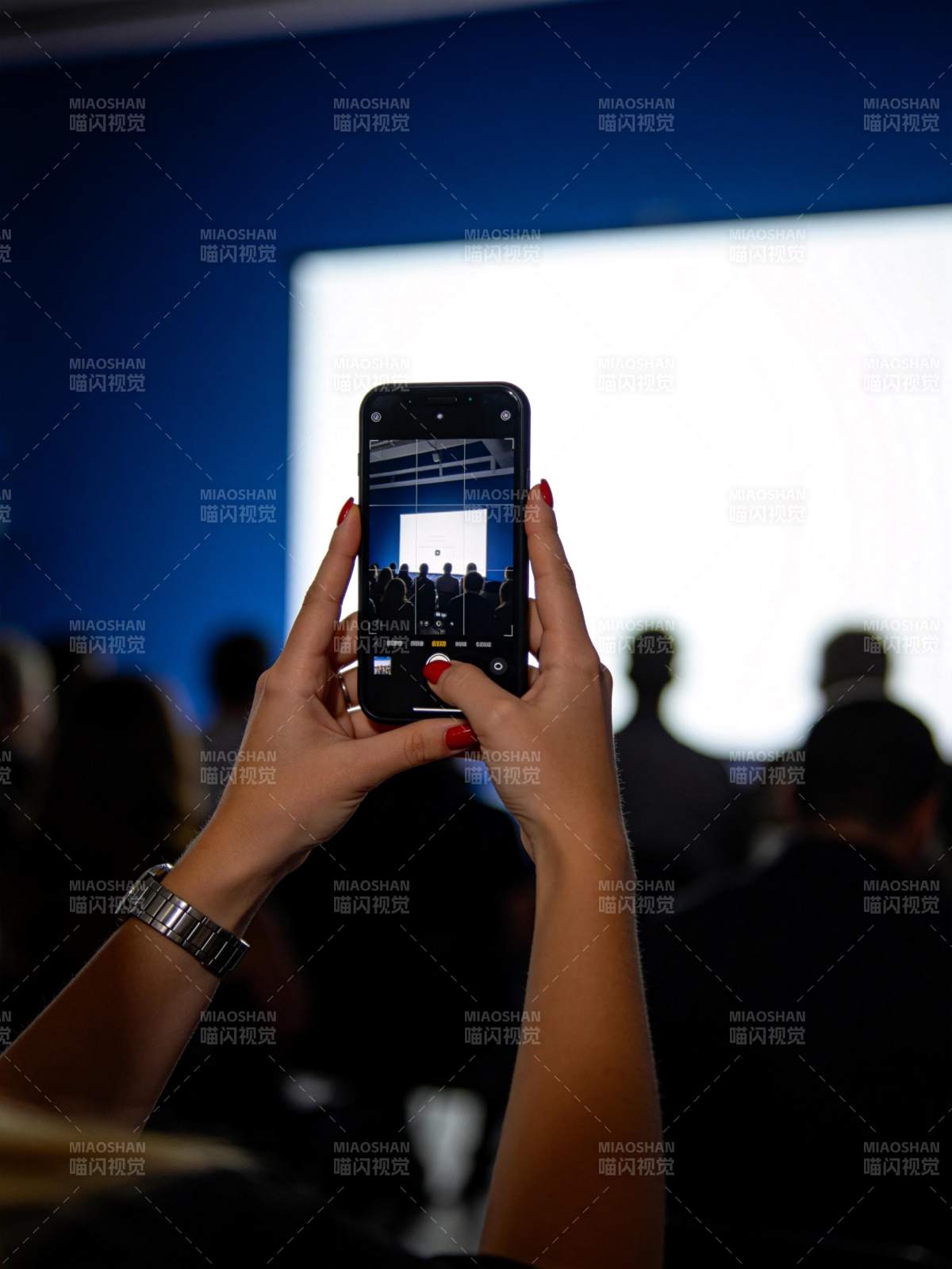 观众用手机拍摄舞台演讲现场画面图片