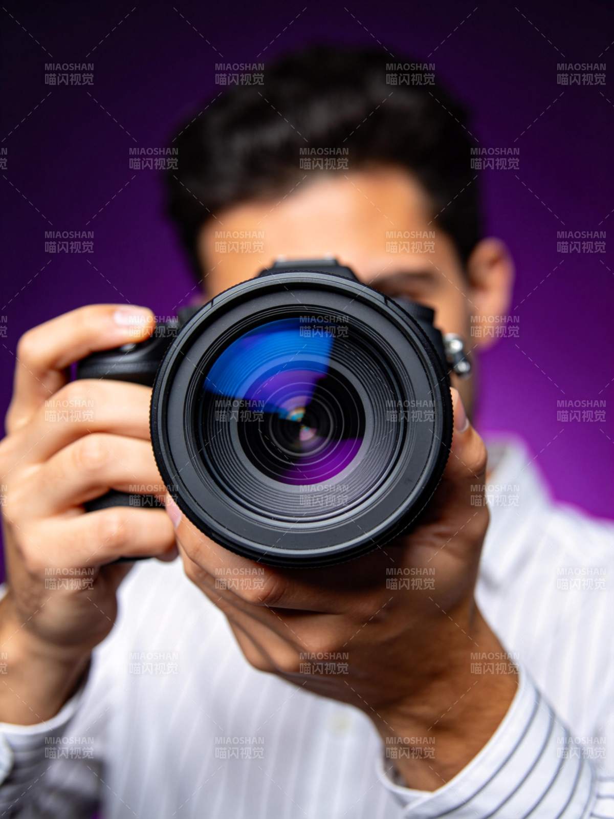 男子手持单反相机对准镜头拍摄图片