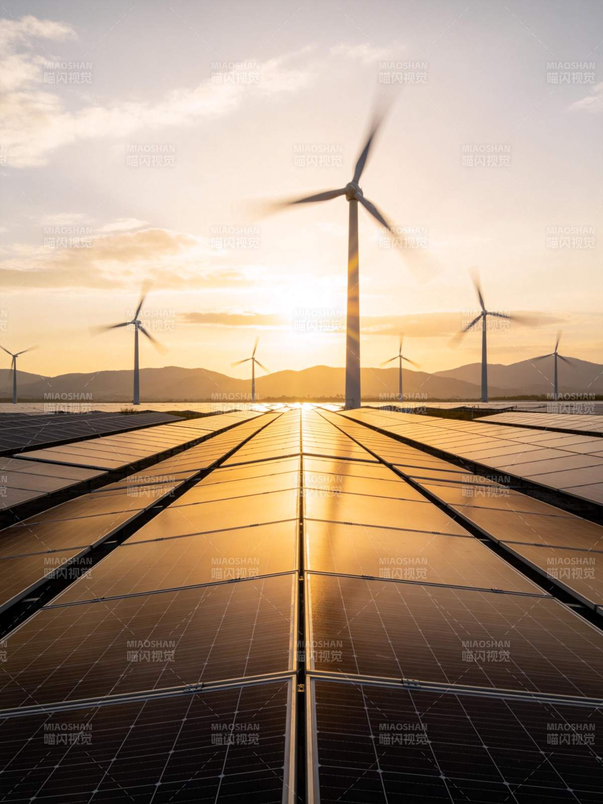 夕阳下光伏板阵列与风力发电机并列运行图片