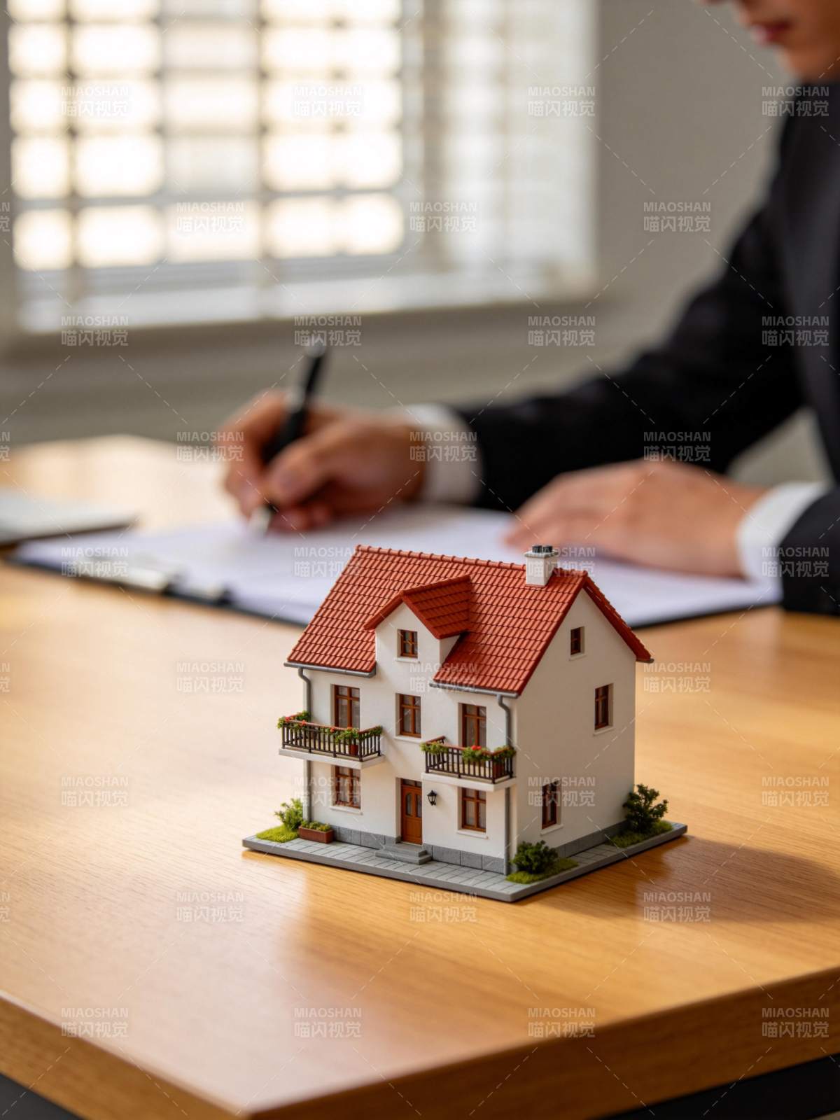 办公桌上摆放房屋模型与签约场景图片