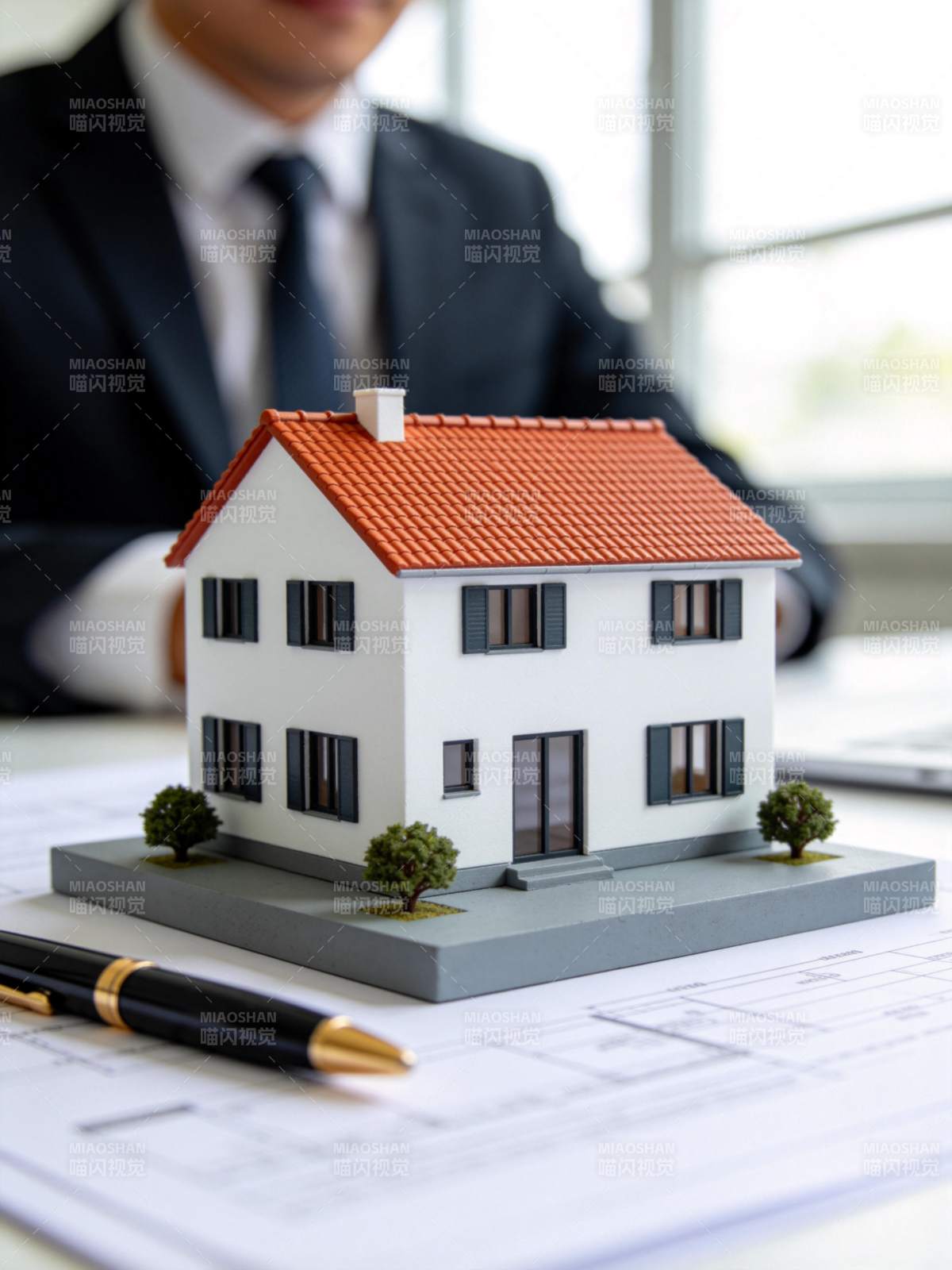 办公桌上房屋模型与图纸及商务人士图片