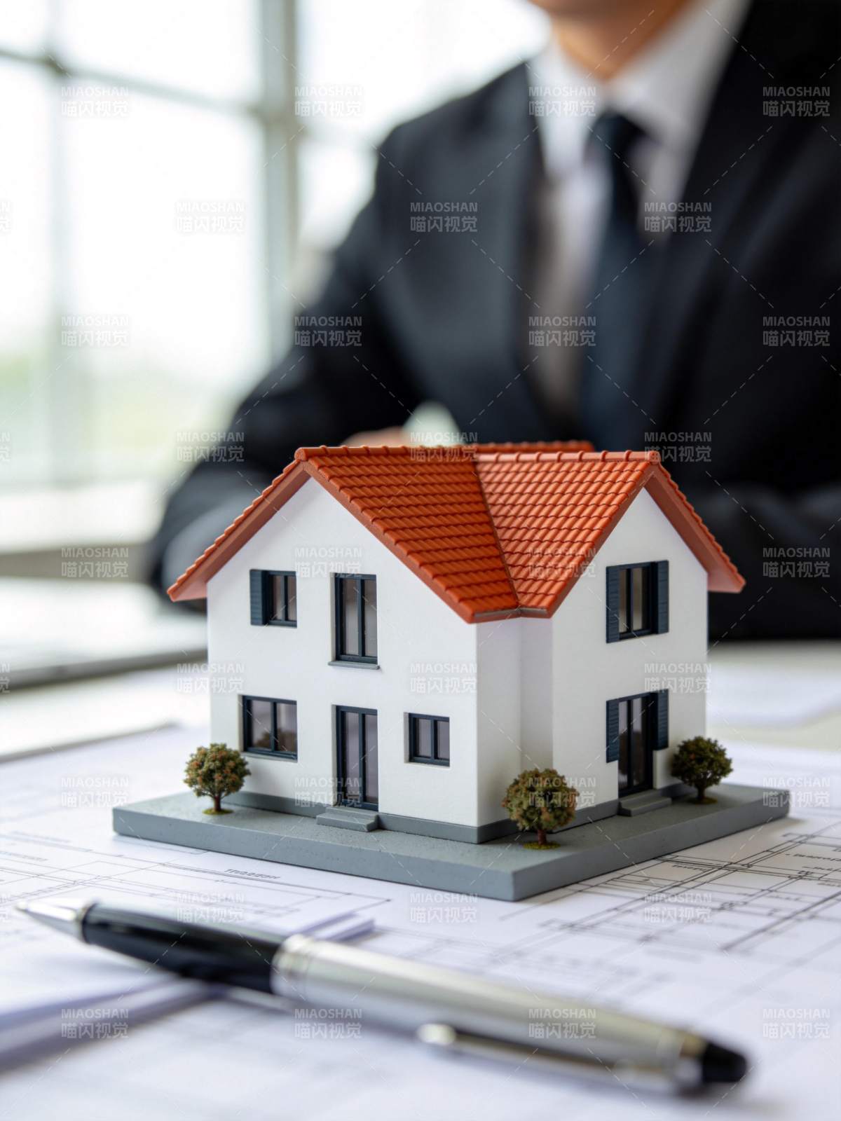 办公桌上房屋模型与图纸及签字笔图片
