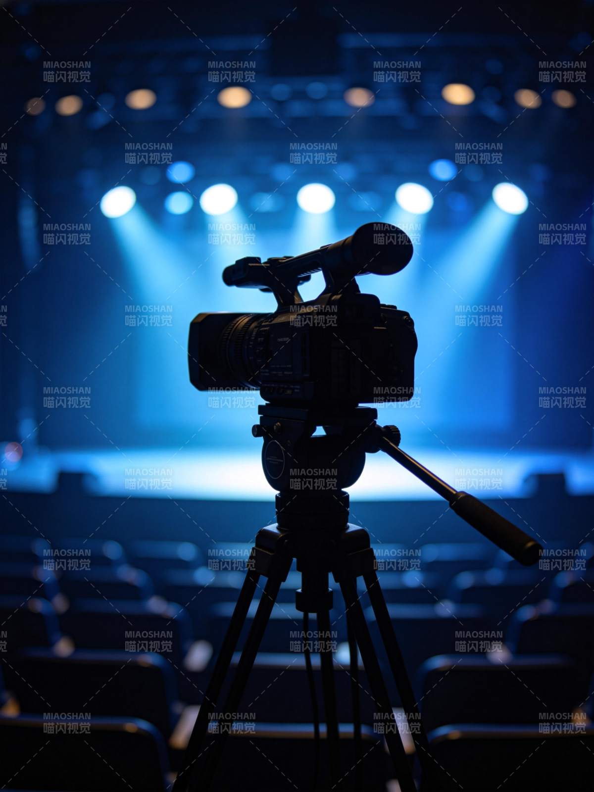 舞台灯光下架设在三脚架上的专业摄像机图片
