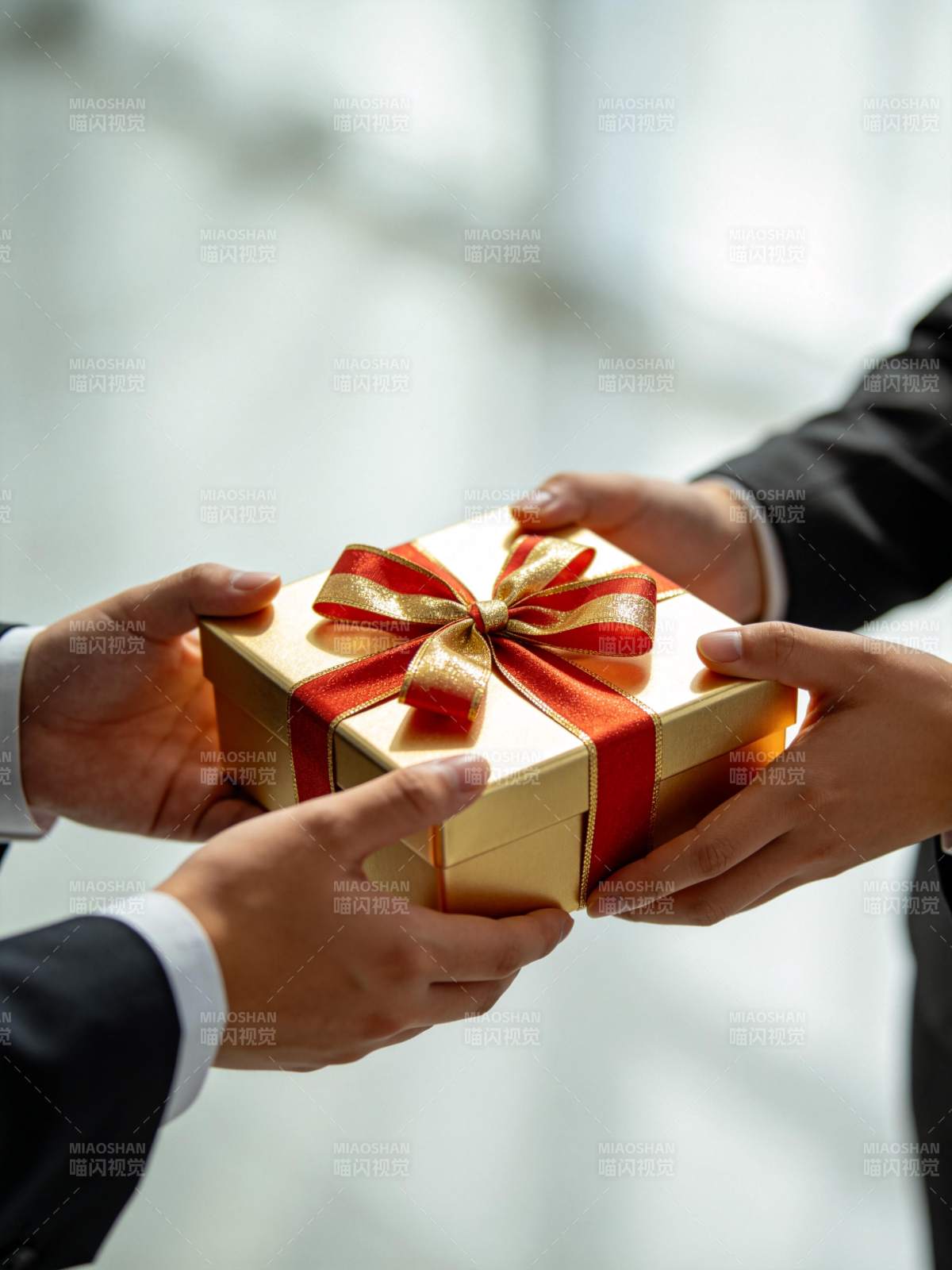 两人交接金色礼盒红色蝴蝶结包装礼物图片