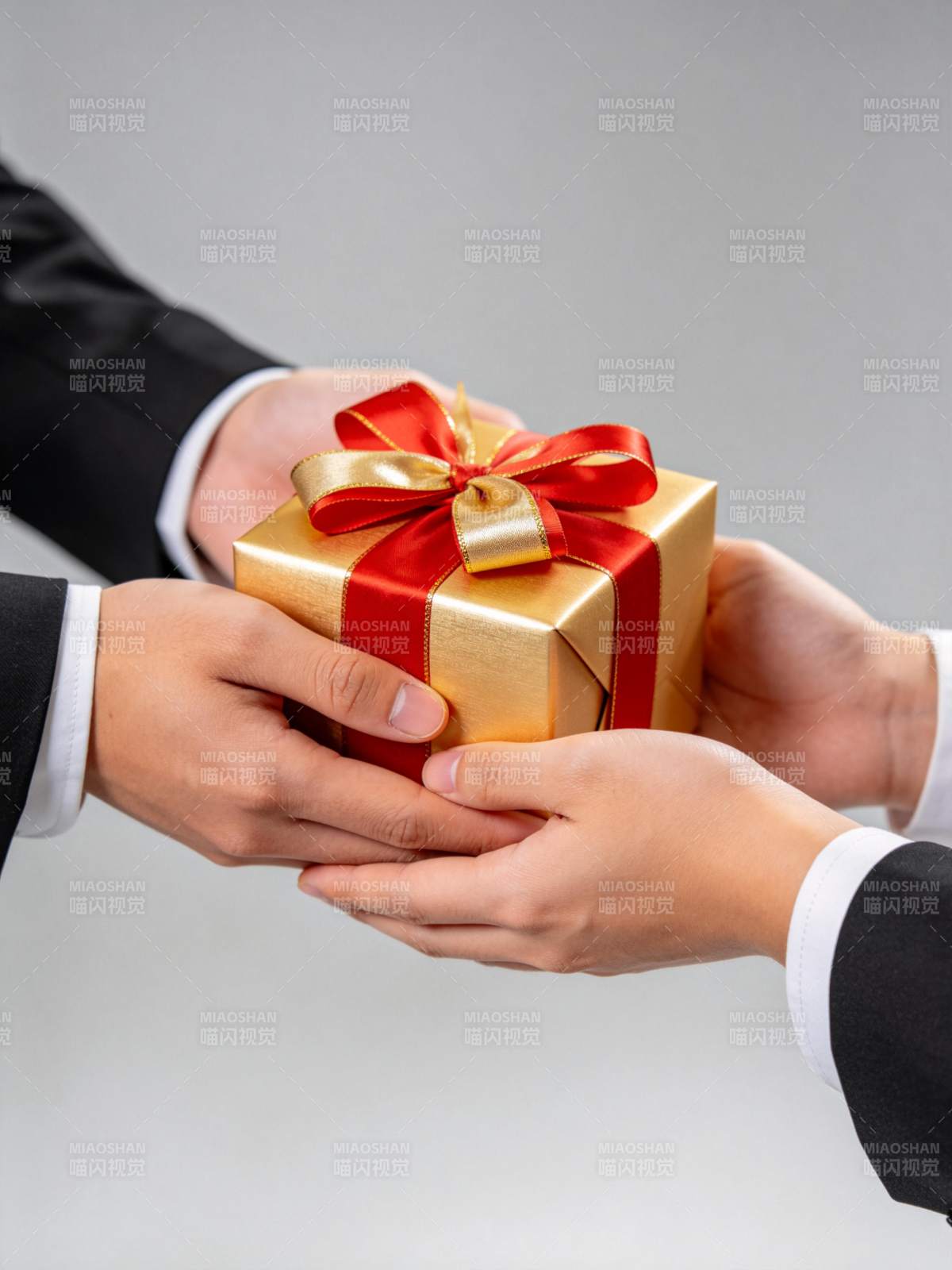 两人交接金色礼盒红色丝带装饰礼物图片