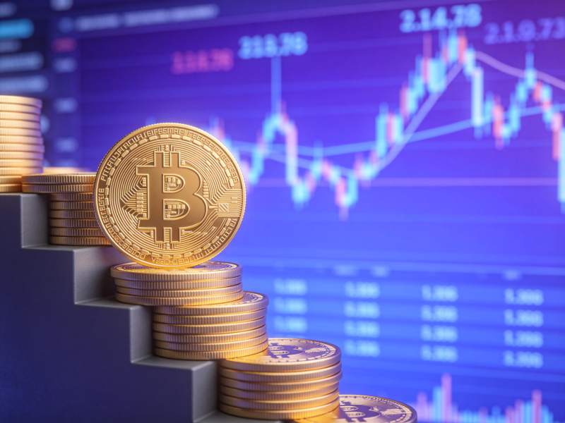 金色比特币硬币堆叠在阶梯上背景为金融图表图片