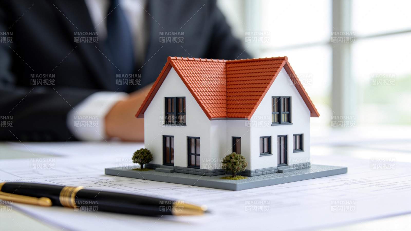 办公桌上房屋模型与图纸文件特写图片