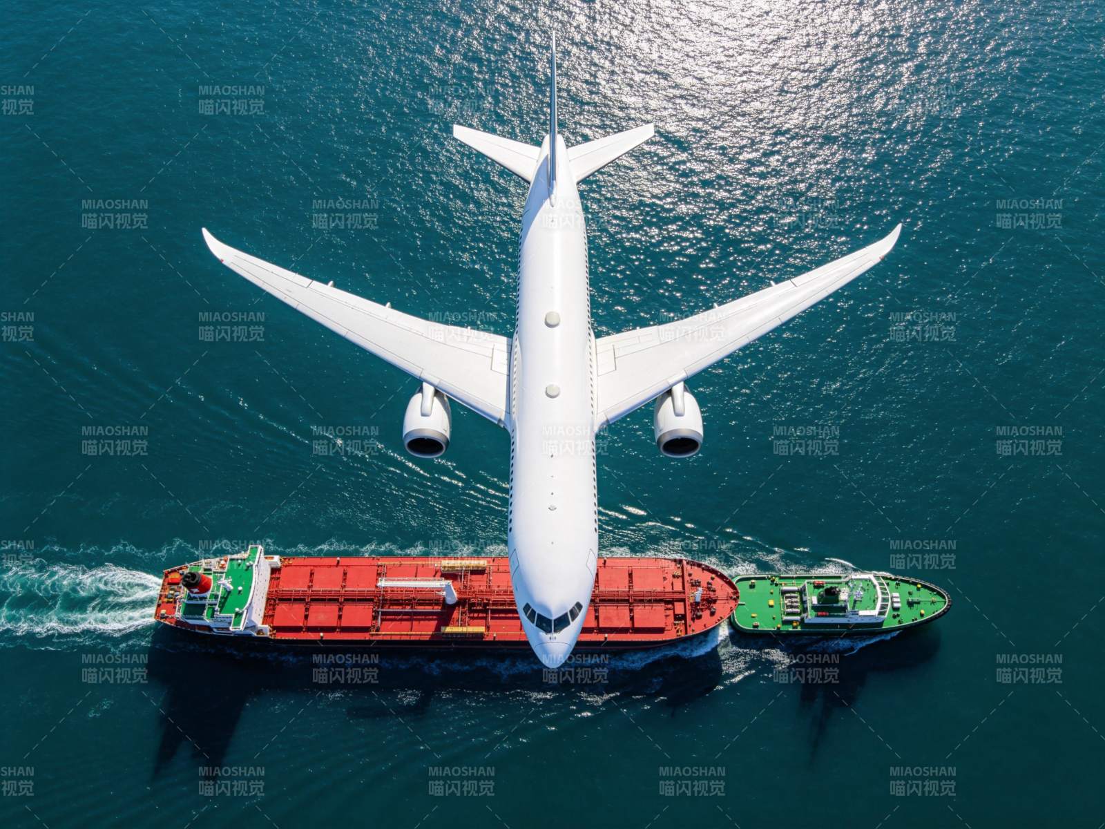 白色客机飞越红色货轮与绿色拖船海面图片