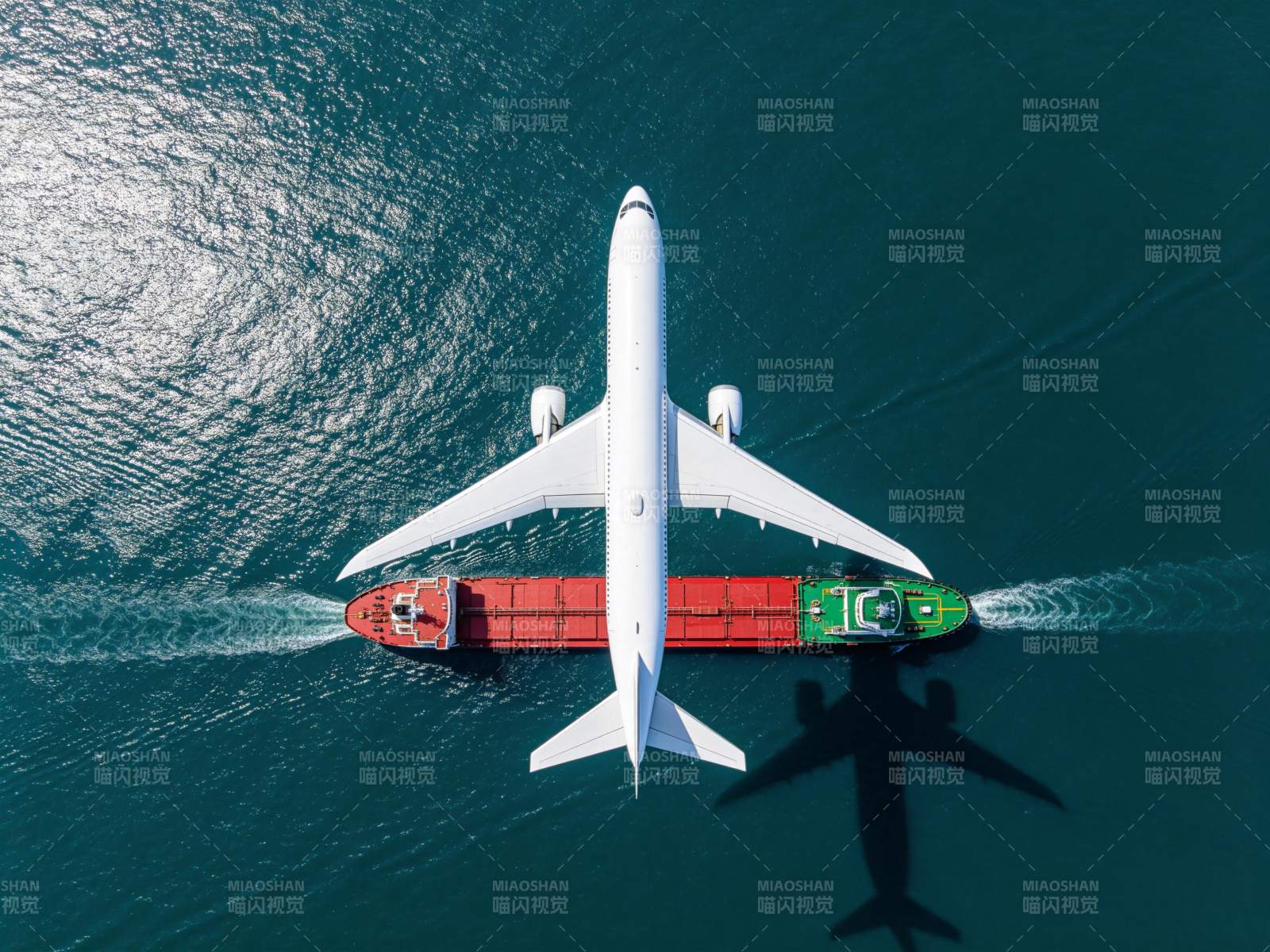 白色客机飞越红色货轮海面航拍图图片