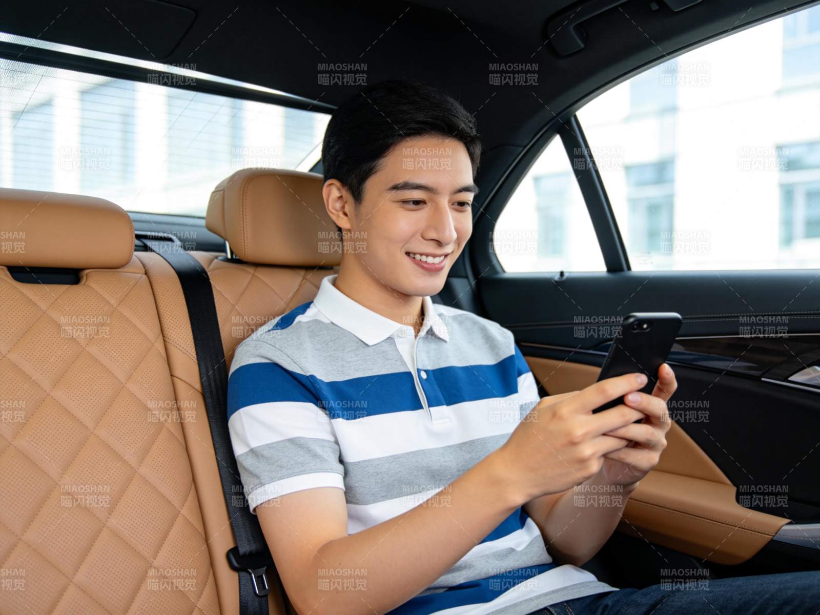 年轻男子坐在汽车后座使用智能手机图片