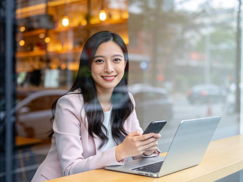 女性在咖啡馆使用笔记本电脑和手机工作图片